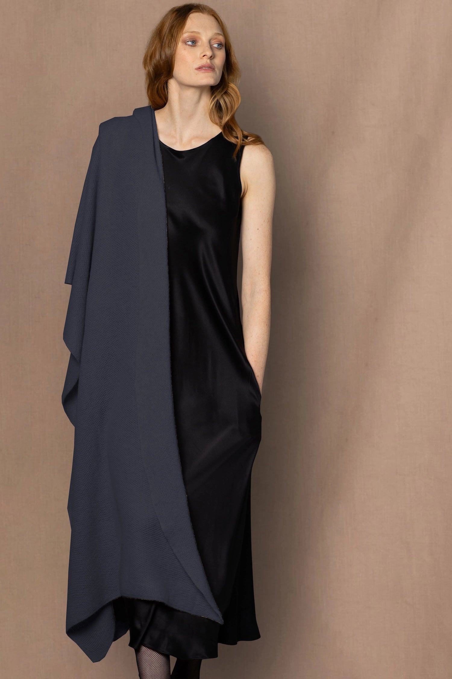 Woman wearing a navy blue cashmere wrap shawl over a black silk dress