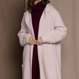 woman wearing a long cashmere coat cardigan in pale pink over burgundy cashmere sweater and burgundy silk trousers