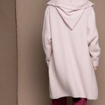 woman wearing a long cashmere coat cardigan in pale pink over burgundy silk trousers