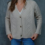 a woman wear a cashmere aran cardigan in beige with horn buttons over jeans