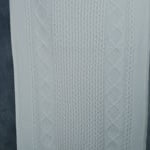 a woman wears a large cashmere aran throw blanket in cream