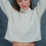 a woman wears a traditional Irish aran cropped turtleneck sweater made from pure 100% cashmere in cream