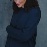 a woman wear a cashmere hoodie sweater in an ink blue colour over jeans