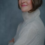 a woman wears a traditional Irish aran turtleneck sweater made from pure 100% cashmere in cream