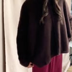 video of a woman wearing an oversized cashmere sweater in dark brown with matching cashmere beanie hat over silk trousers in burgundy