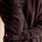 video of a woman wearing cashmere fingerless gloves in dark brown with matching cashmere beanie hat and cashmere snood and cashmere sweater with burgundy silk pants