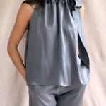 video of a woman wearing a metallic silk halter top in pewter grey with matching silk trousers in metallic pewter grey.