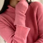 video of a woman wearing cashmere fingerless gloves in dusty rose pink with matching cashmere beanie hat and turtleneck sweater