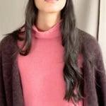 video of a woman wearing a cashmere coat in chocolate brown over a cashmere turtleneck sweater in dusty rose pink and matching cashmere beanie hat in dusty rose pink