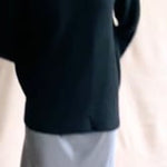 a video of a woman wearing a black cashmere fisherman turtleneck sweater jumper with pewter silk skirt and black leather boots