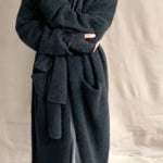 video of a woman wearing a long cashmere coat in dark grey over black cashmere turtleneck sweater and pewter silk skirt with black leather boots