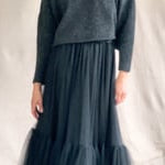 video of a woman wearing a cropped cashmere oversized cashmere sweater in black with metallic silver lurex thread and tulle skirt in black