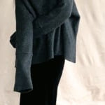 video of a woman wearing an oversized cashmere sweater with cowl neck in black with silver metallic lurex thread over silk velvet skirt in black