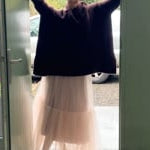 video of a woman wearing an oversized cashmere sweater with cowl neck in dark brown over  pale pink tulle skirt