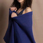 A woman wears a bright blue cashmere shawl wrapped around her