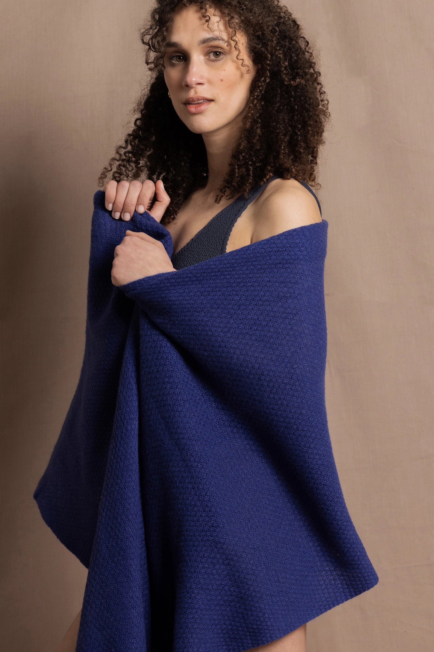 A woman wears a bright blue cashmere shawl wrapped around her