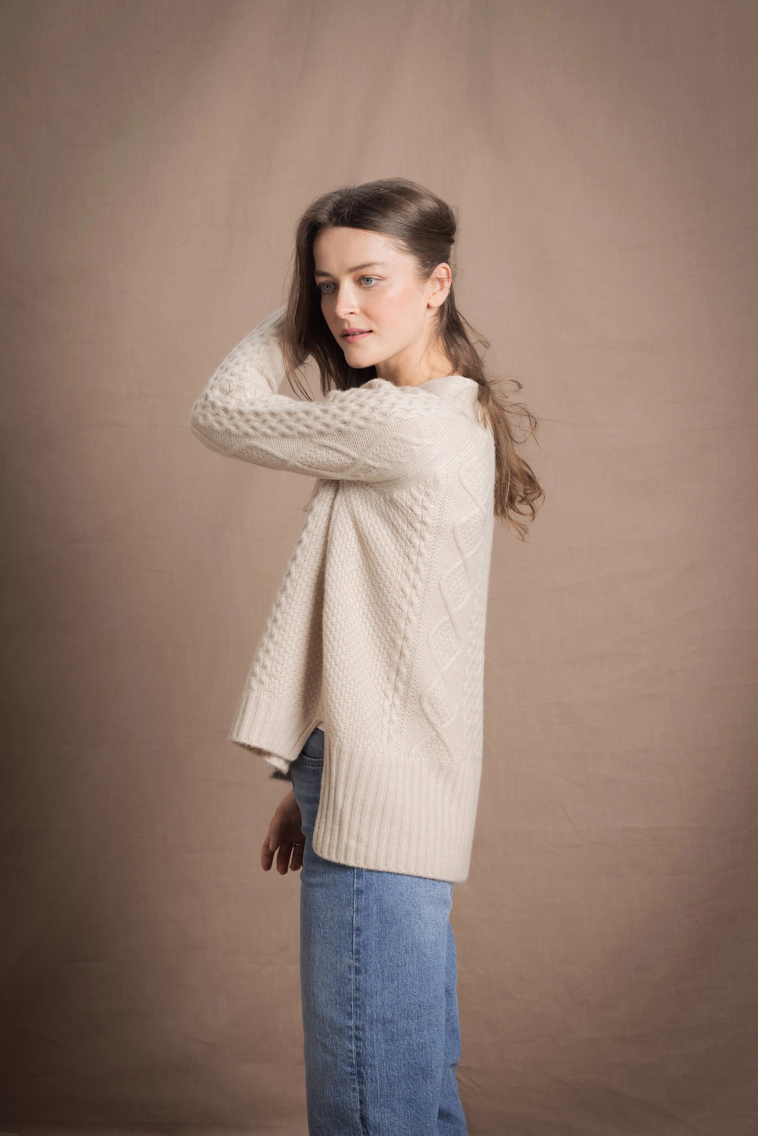 A lady wears a traditional Irish Cashmere Aran Cardigan Sweater in Beige