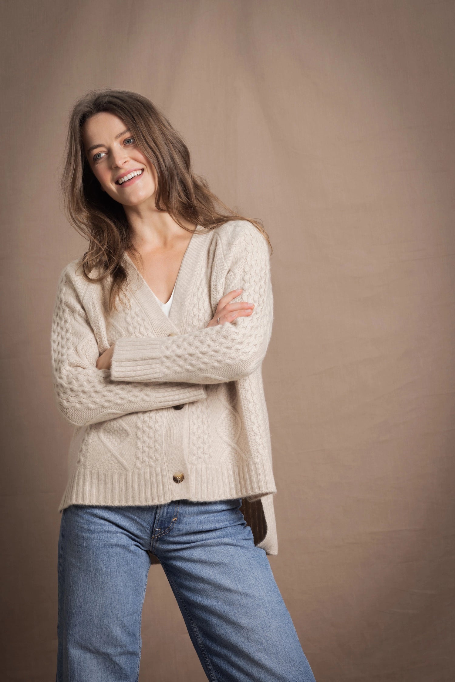 A lady wears a traditional Irish Cashmere Aran Cardigan Sweater in Beige