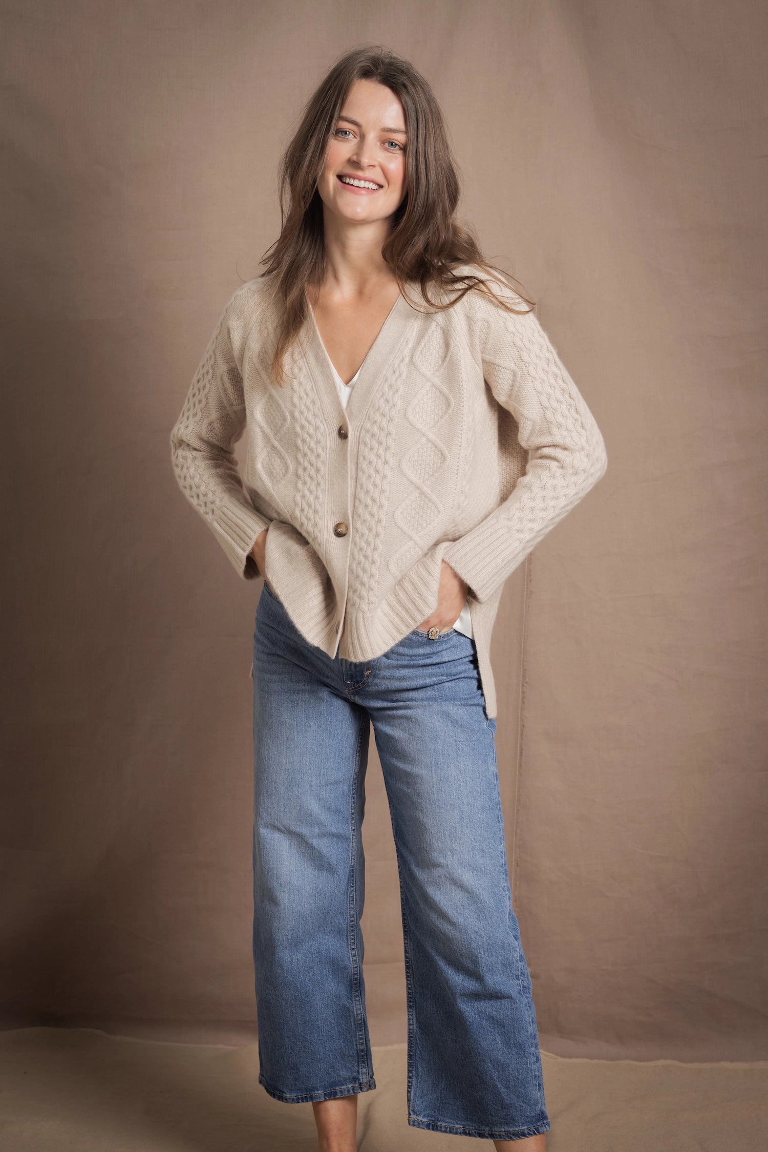 A lady wears a traditional Irish Cashmere Aran Cardigan Sweater in Beige