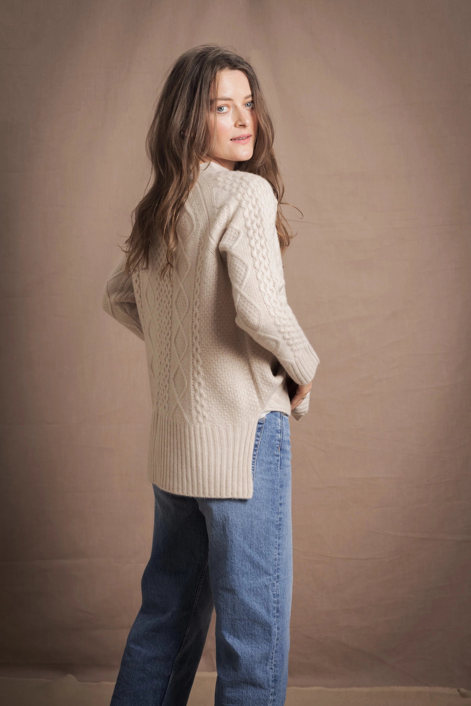 A lady wears a traditional Irish Cashmere Aran Cardigan Sweater in Beige