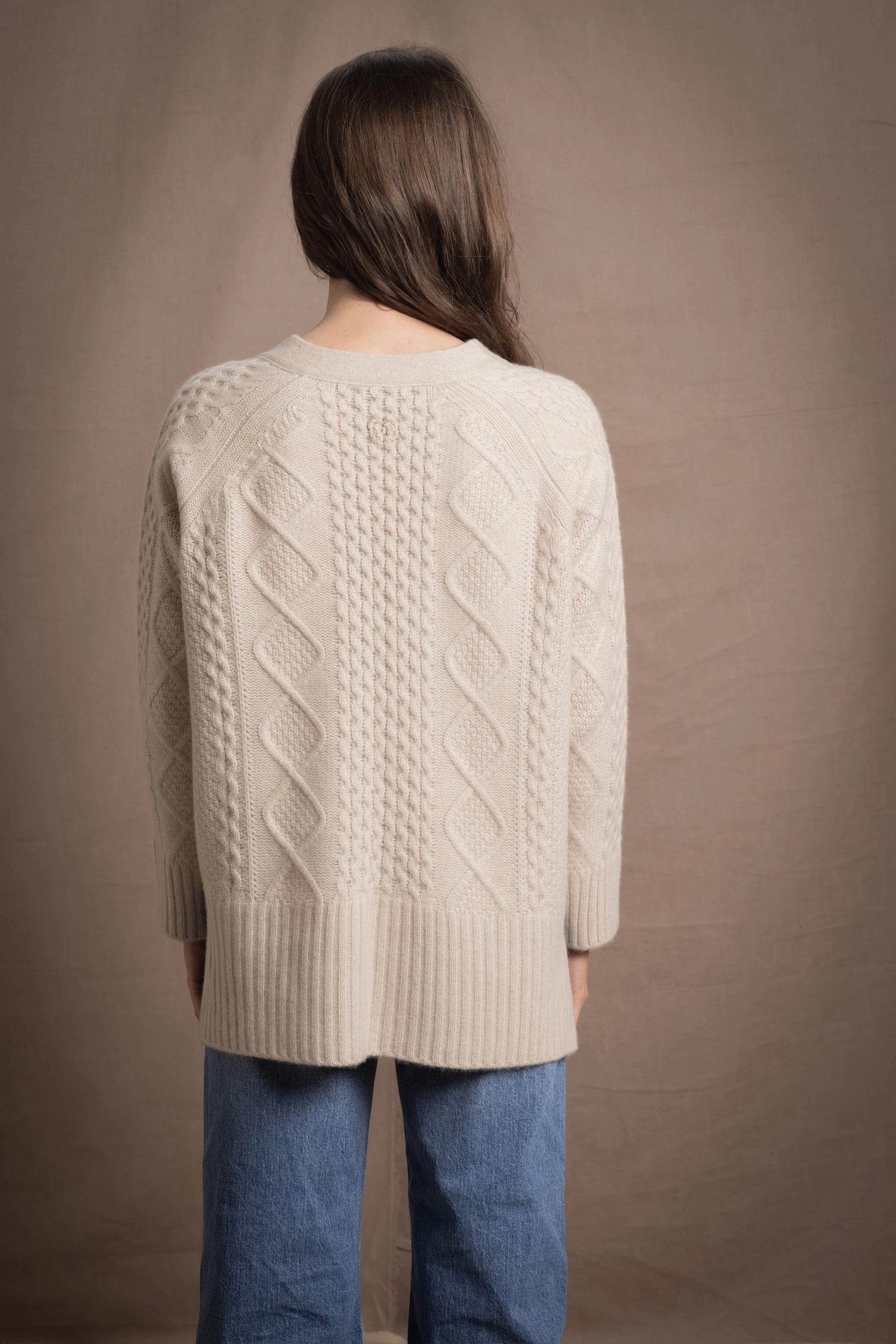 A lady wears a traditional Irish Cashmere Aran Cardigan Sweater in Beige