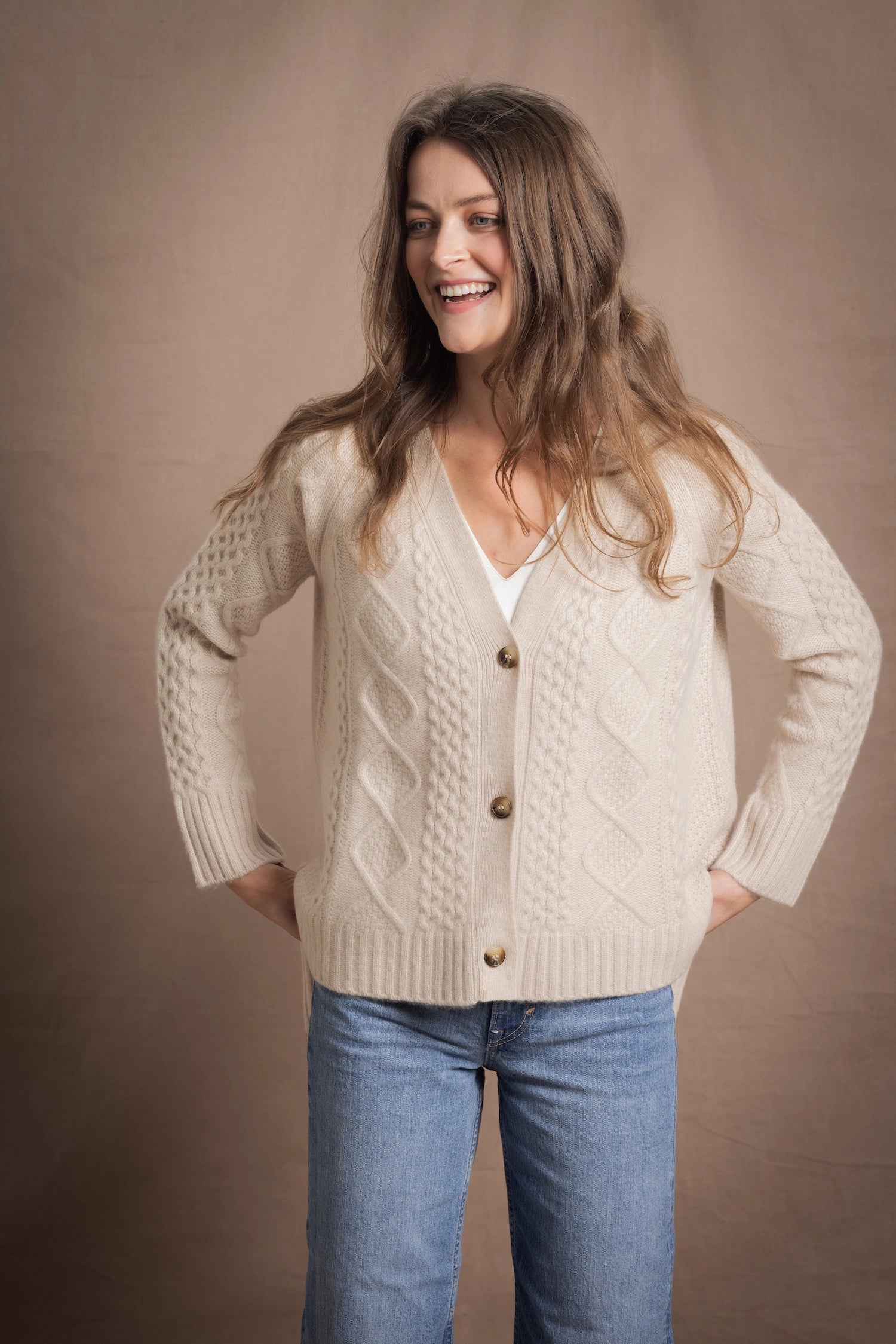 A lady wears a traditional Irish Cashmere Aran Cardigan Sweater in Beige
