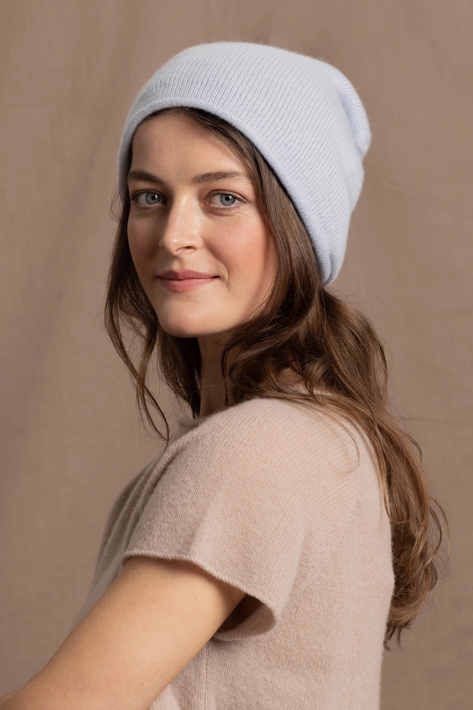 a lady wears a luxury pure cashmere beanie hat in pale blue
