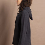 lady looks sideways wearing an oversized pure cashmere hoodie sweater in grey blue colour