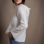 A lady wears a relaxed 100% pure cashmere sweater in a pointelle texture in white with jeans