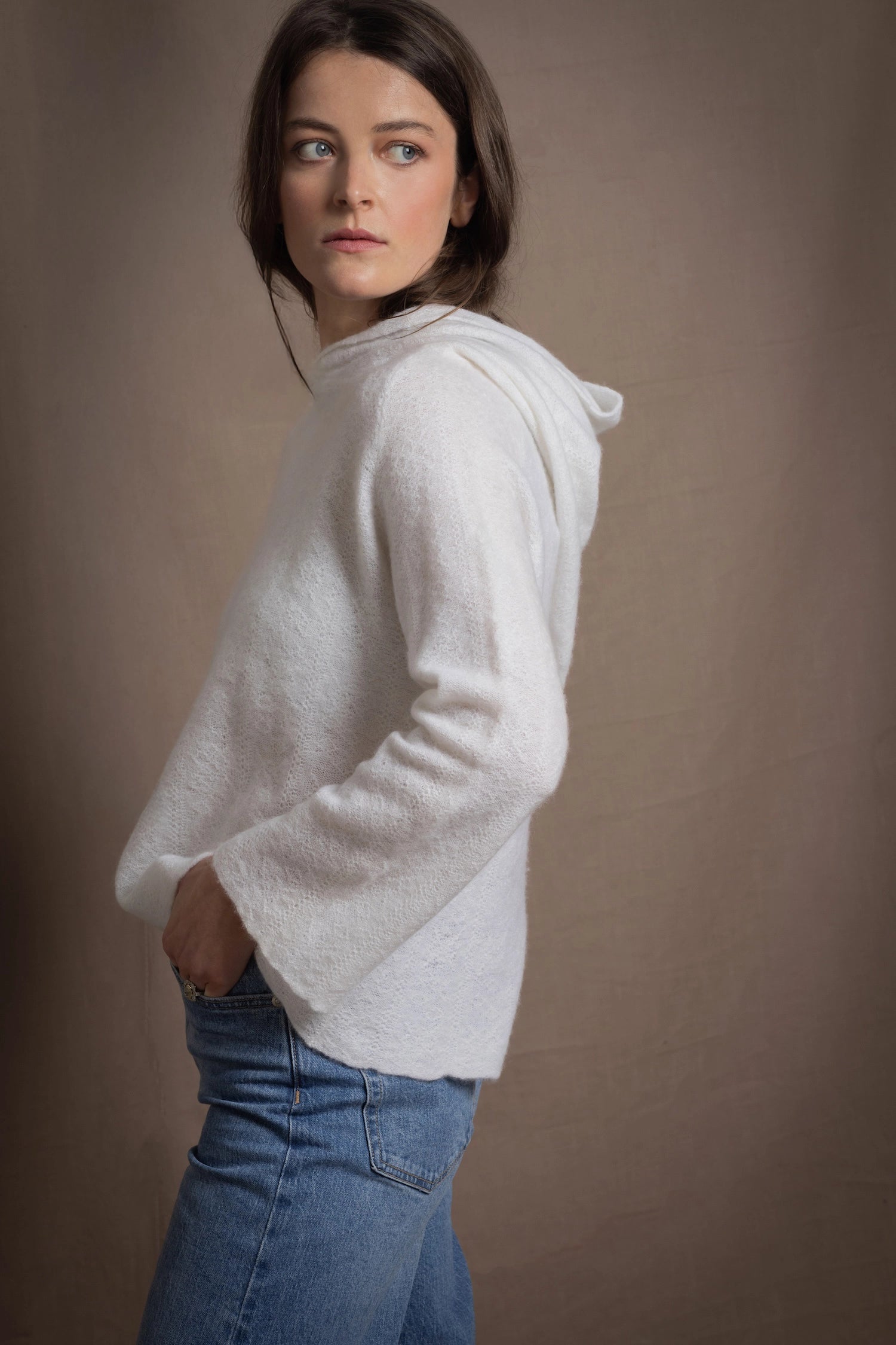 A lady wears a relaxed 100% pure cashmere sweater in a pointelle texture in white with jeans