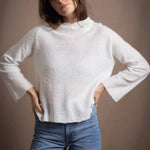 A lady wears a relaxed 100% pure cashmere sweater in a pointelle texture in white with jeans