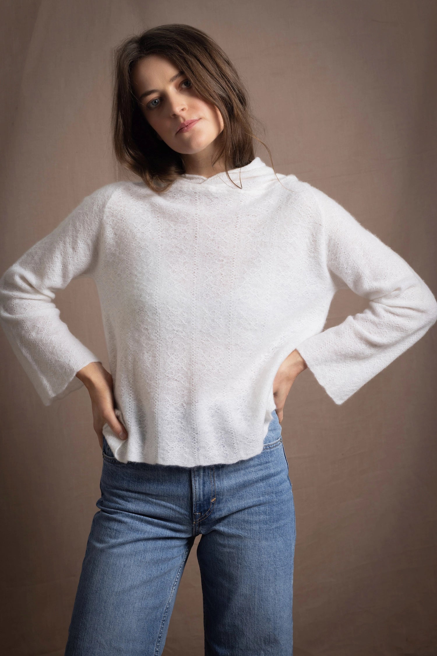 A lady wears a relaxed 100% pure cashmere sweater in a pointelle texture in white with jeans