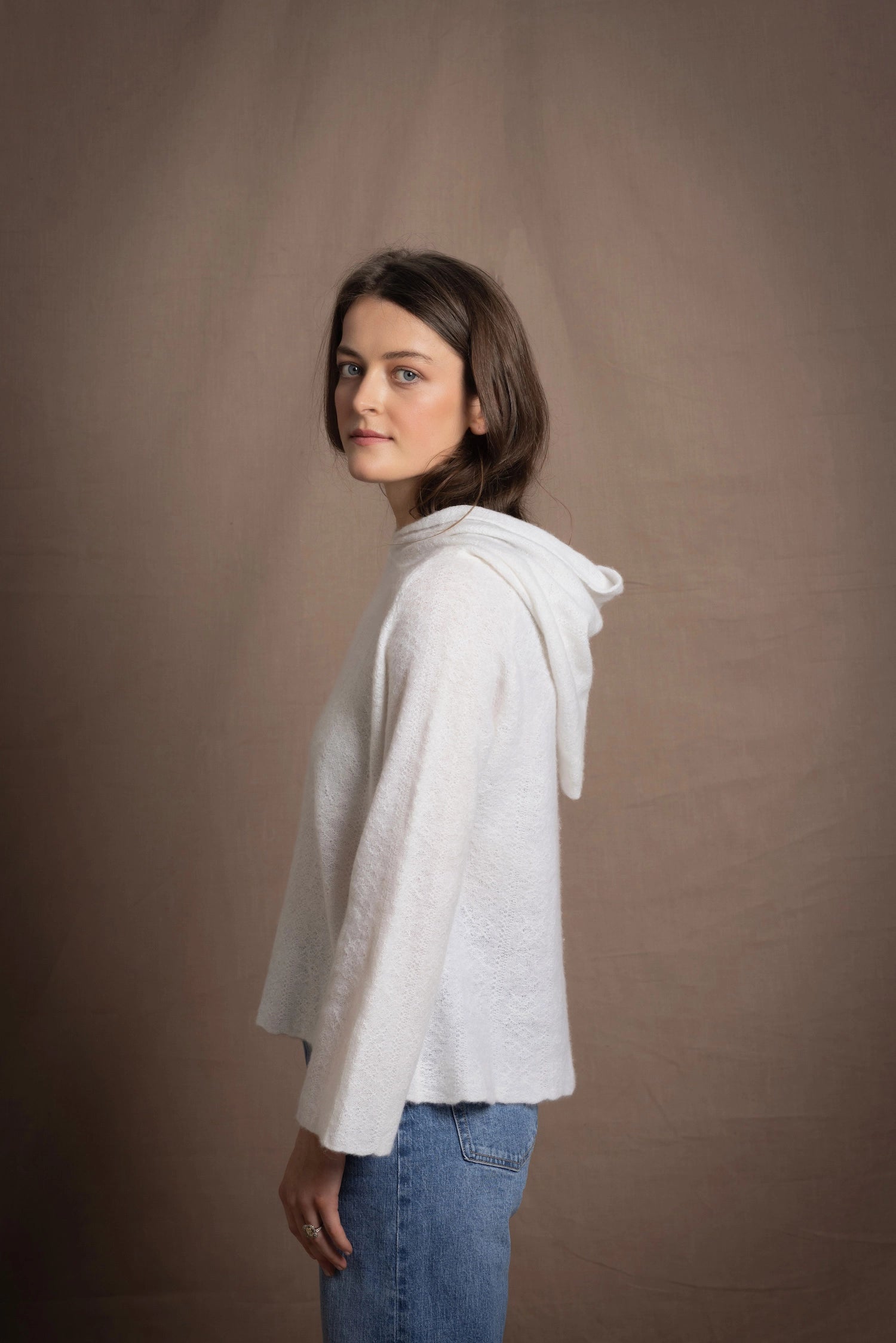 A lady wears a relaxed 100% pure cashmere jumper in a pointelle texture in white with jeans