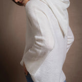A lady wears a relaxed 100% pure cashmere sweater in a pointelle texture in white with jeans
