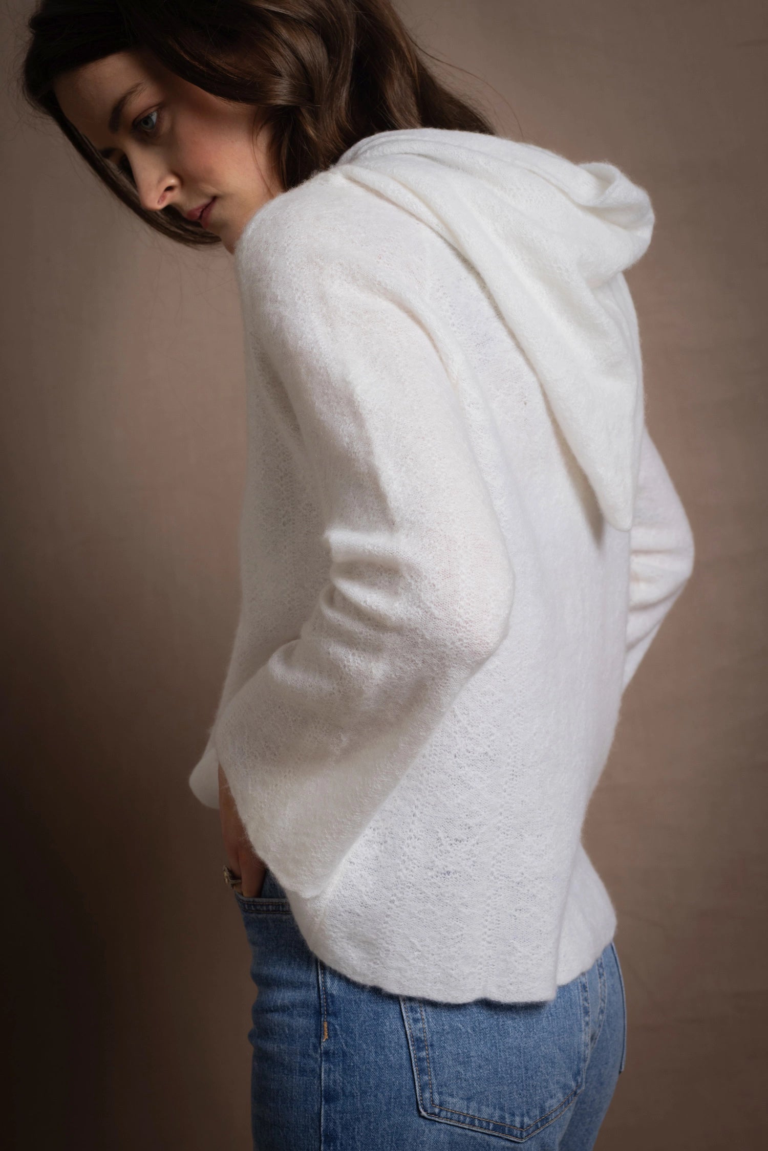A lady wears a relaxed 100% pure cashmere sweater in a pointelle texture in white with jeans