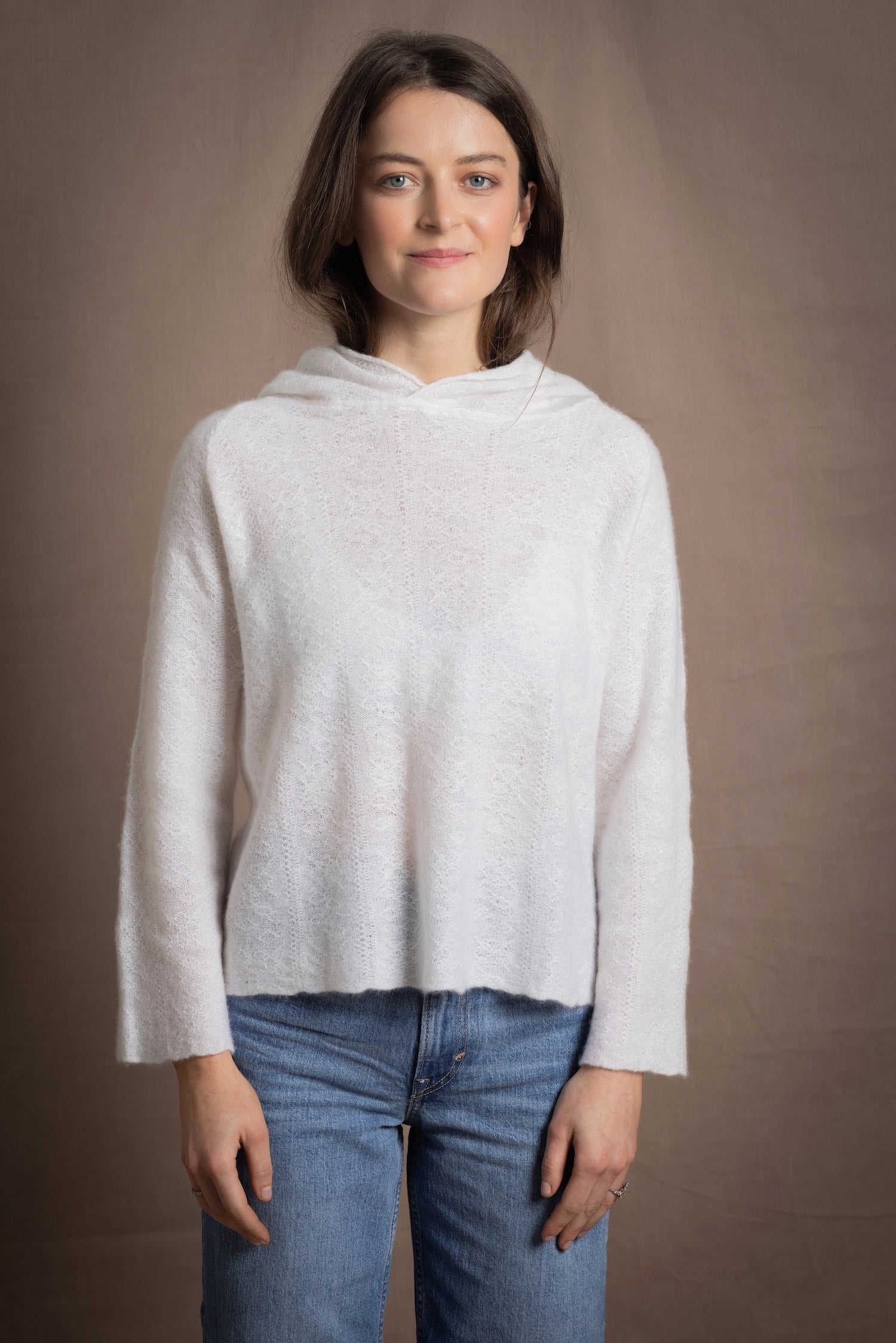 A lady wears a relaxed 100% pure cashmere sweater in a pointelle texture in white with jeans