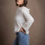 A lady wears a relaxed 100% pure cashmere sweater in a pointelle texture in white with jeans