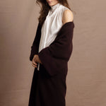 A woman wears a 100% silk pussybow sleeveless blouse in white with a chocolate brown and purple cashmere coat on top