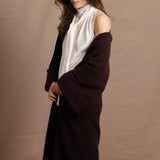 A woman wears a 100% silk pussybow sleeveless blouse in white with a chocolate brown and purple cashmere coat on top