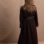 A woman wears a 100% silk pussybow sleeveless blouse in white with a chocolate brown and purple cashmere coat on top and cinched with leather obi belt