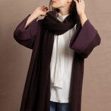 A woman wears a 100% silk pussybow sleeveless blouse in white with a chocolate brown and purple cashmere coat on top with matching wrap