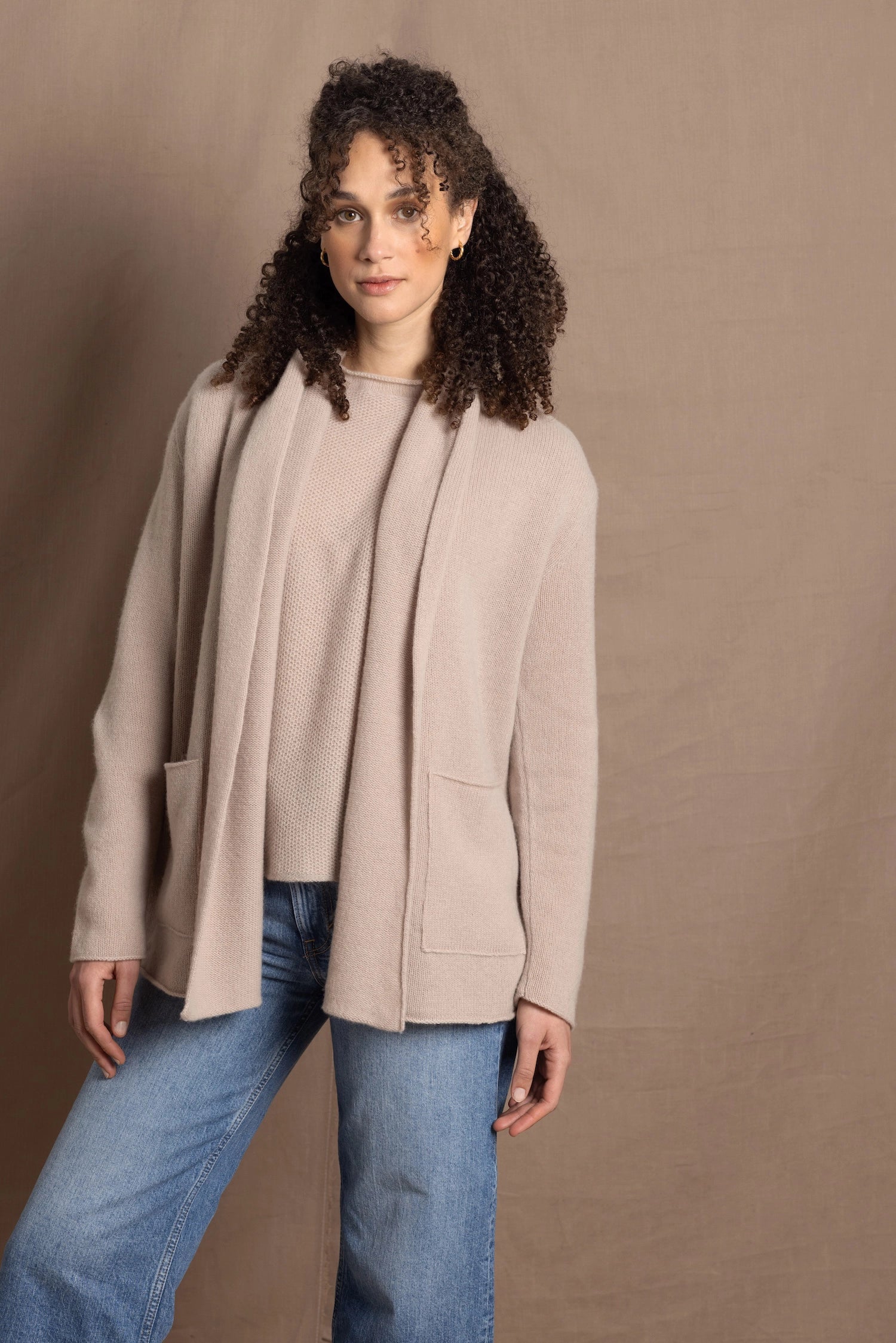 Lady wears beige coloured open cashmere cardigan over matching cashmere tee 