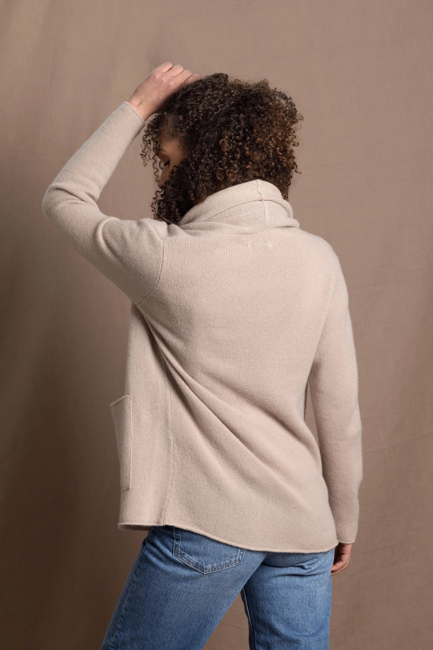 Lady wears beige coloured open cashmere cardigan over matching cashmere tee 
