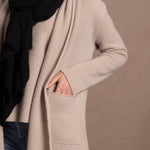 Lady wears beige coloured open cashmere cardigan over matching cashmere tee  and black scarf