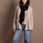 Lady wears beige coloured open cashmere cardigan over matching cashmere tee with black scarf