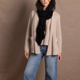Lady wears beige coloured open cashmere cardigan over matching cashmere tee with black scarf
