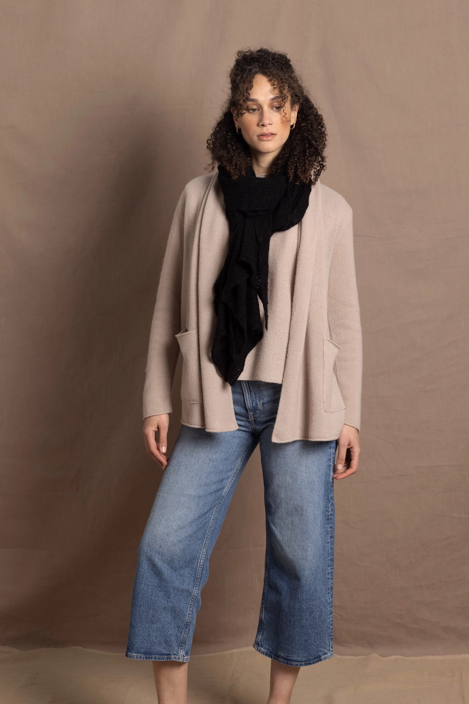 Lady wears beige coloured open cashmere cardigan over matching cashmere tee with black scarf
