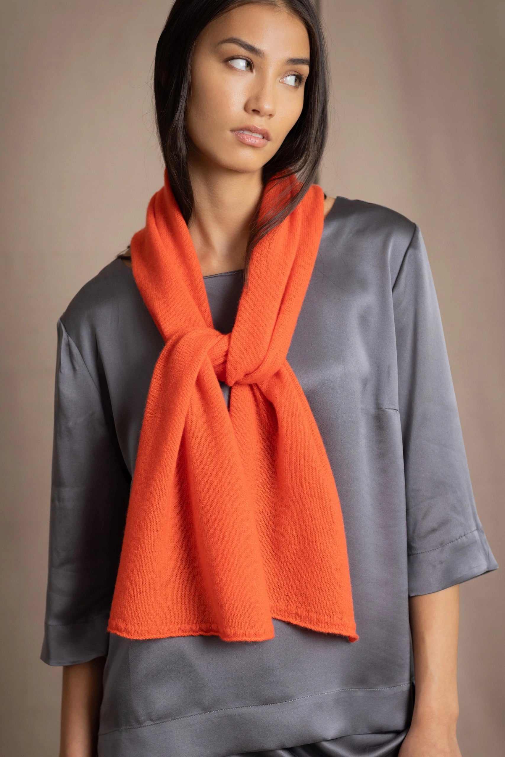 a woman wears a luxury cashmere scarf in bright orange by Irish Quiet Luxury brand Madigan Cashmere