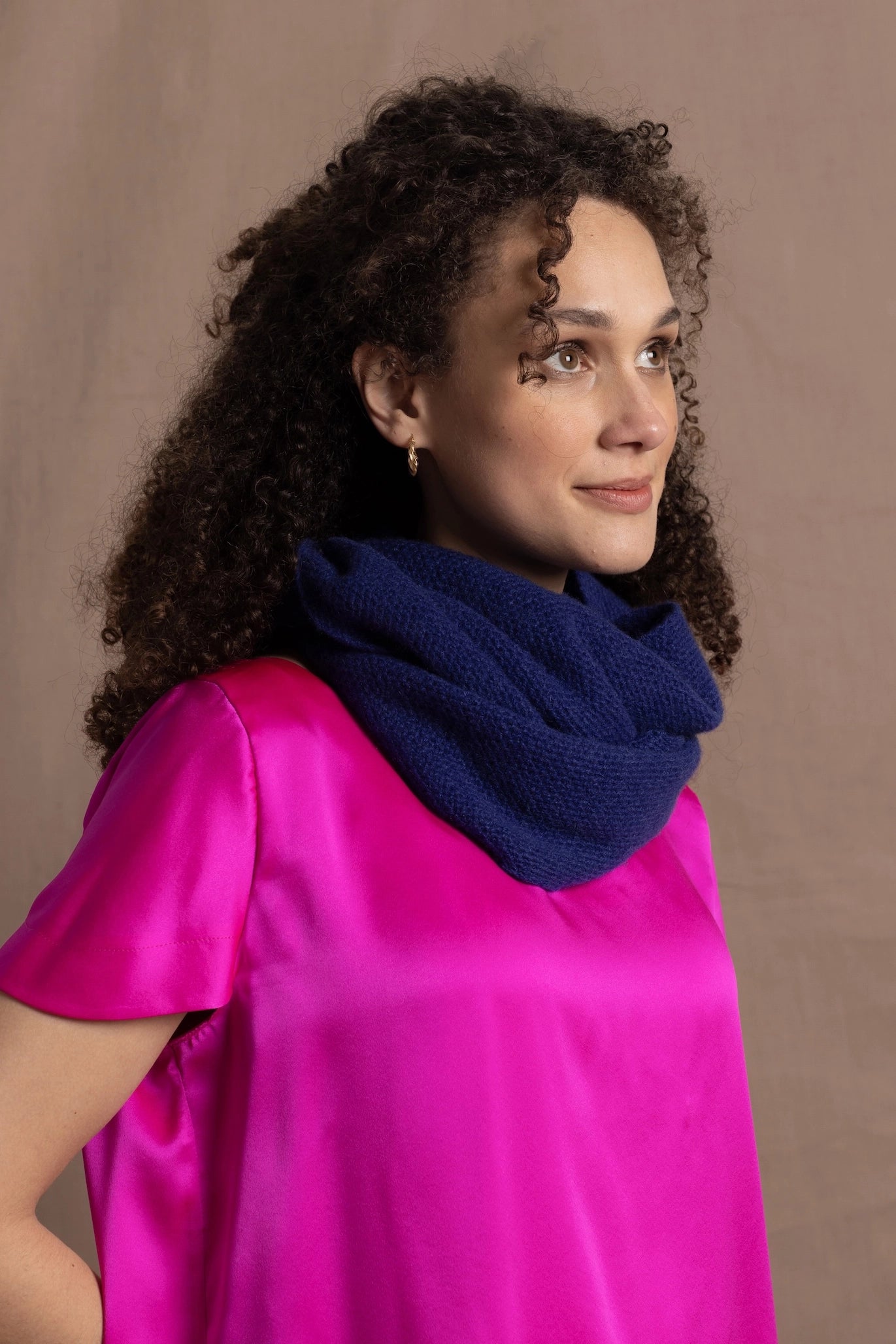 A woman wears a luxury 100% cashmere snood in blue over a bright pink silk tshirt