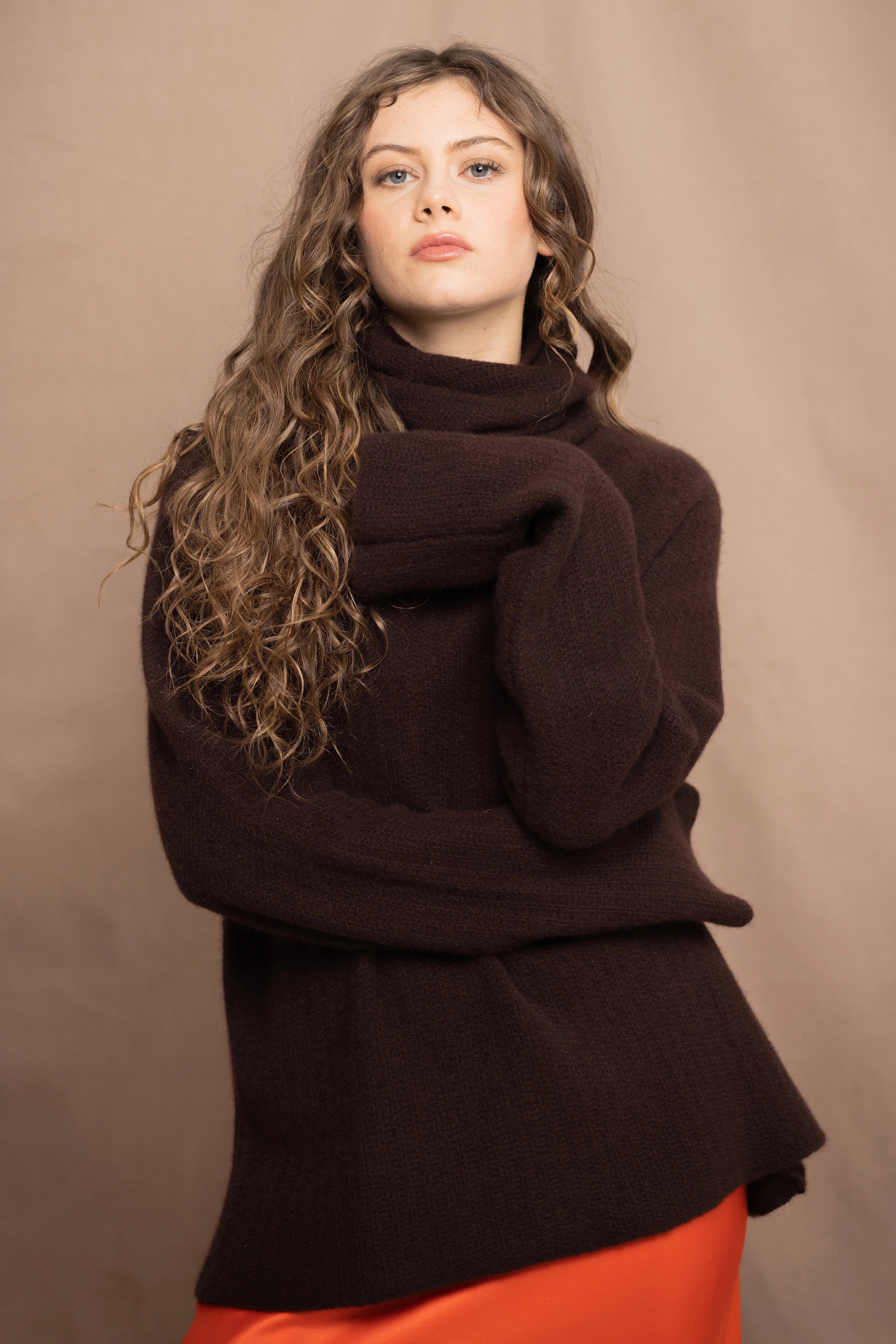 a women wears a pure 100% cashmere turtleneck fisherman sweater in dark brown over a silk skirt in orange by Irish brand Madigan